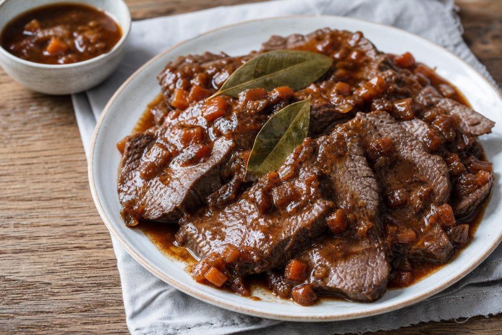 Fette di brasato alla birra con il fondo di cottura e le verdure