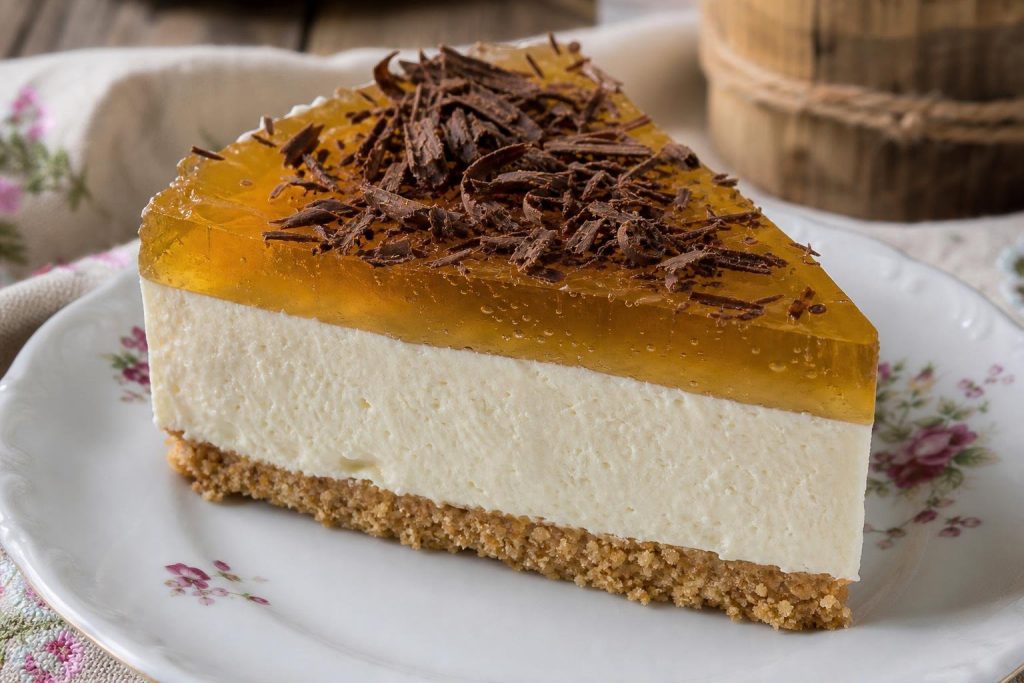 Fetta di cheesecake alla birra con copertura di gelatina dorata e scaglie di cioccolato