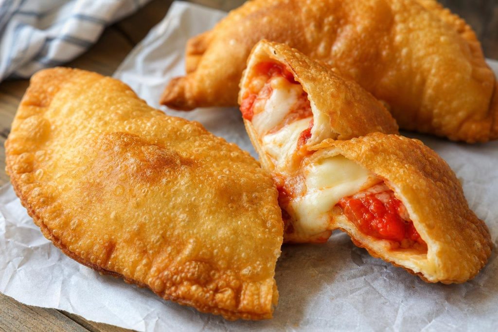 Panzerotti pugliesi alla birra fritti, uno aperto con mozzarella e pomodoro filanti