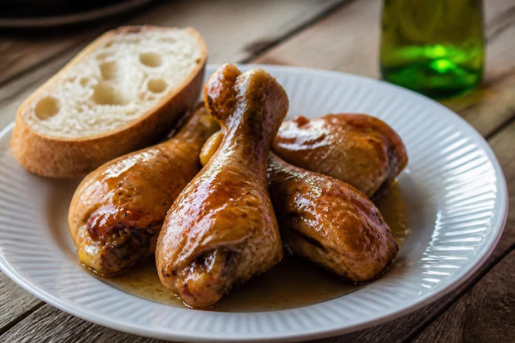 Coscette di pollo alla birra dorate nel piatto con la salsina e una fetta di pane