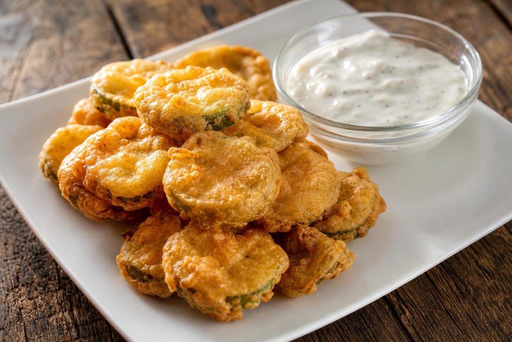 Rondelle di cetriolo sott'aceto fritte in pastella di birra con una ciotolina di salsa